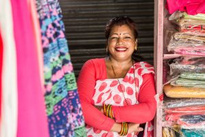 Parwati Parkhi is re-elected as a ward representative for the Dipayal Silgadhi Municipality. She is stood in her textiles workshop wearing pink and smiling.