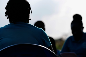 Silouhette of three women from behind wearing blue tshirts.