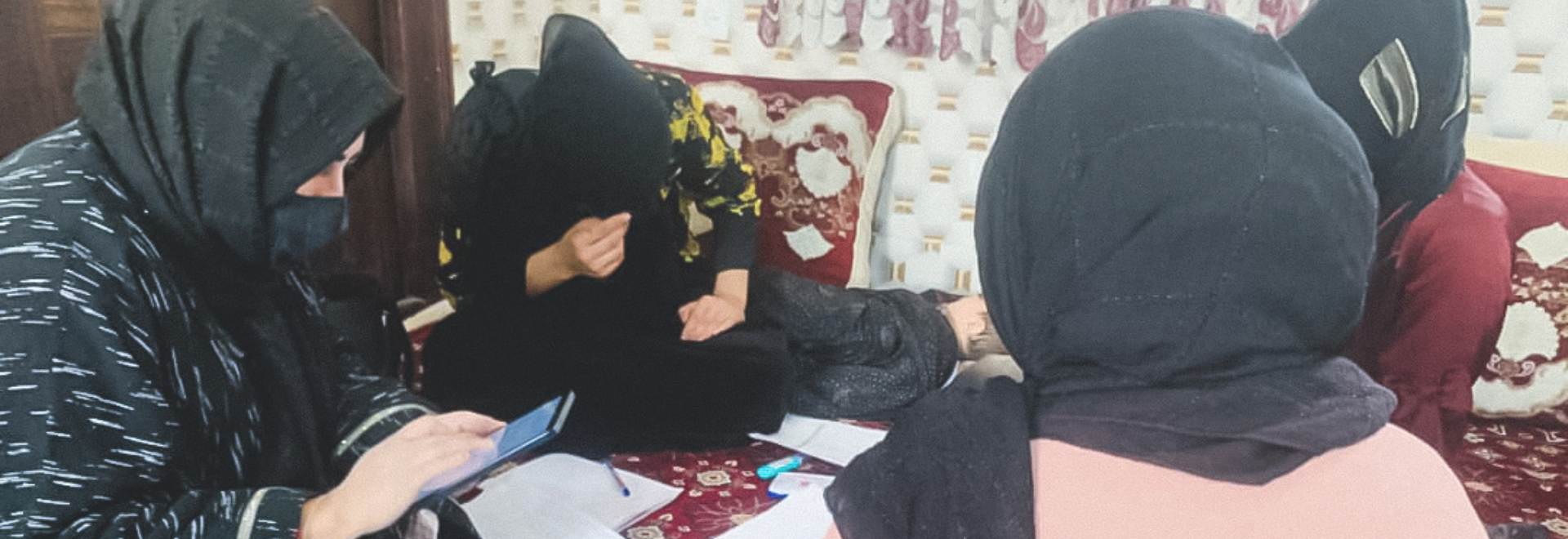 A group of Afghan women sit in a circle in the floor