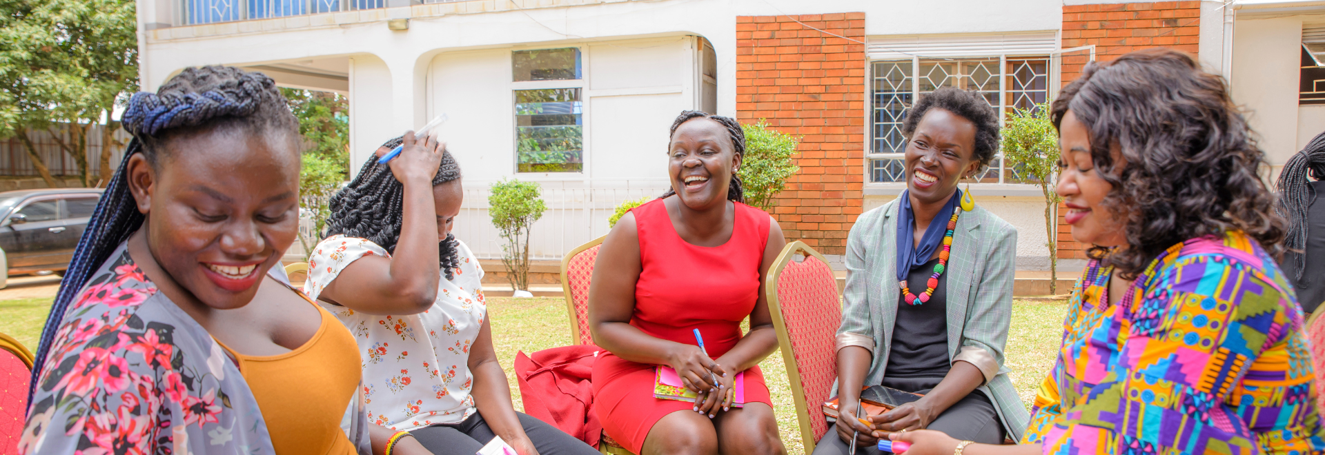 Five women who are members of the WAVE consortium sit together in Uganda laughing and smiling.