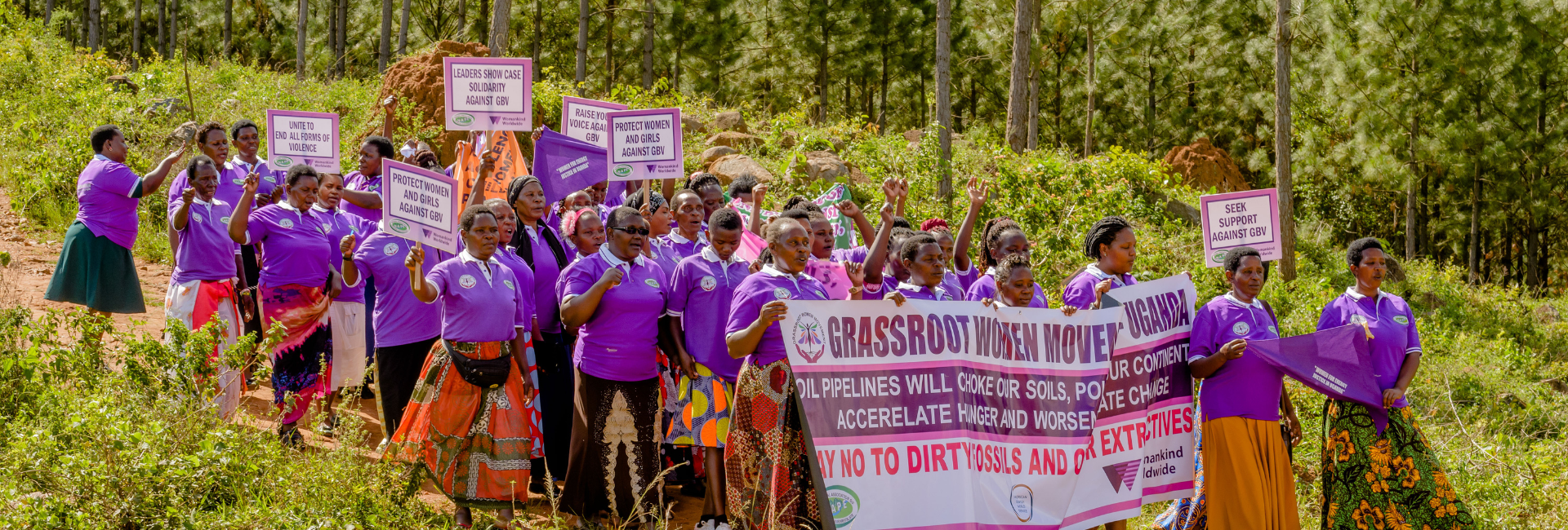 A group of Ugandan activists hold a sign saying 'grassroots women's movment'. They all wear purple NAPE tops.