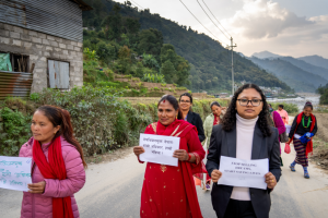 A group of Nepali acticists walk together down a road holding signs that call for end o trafficking